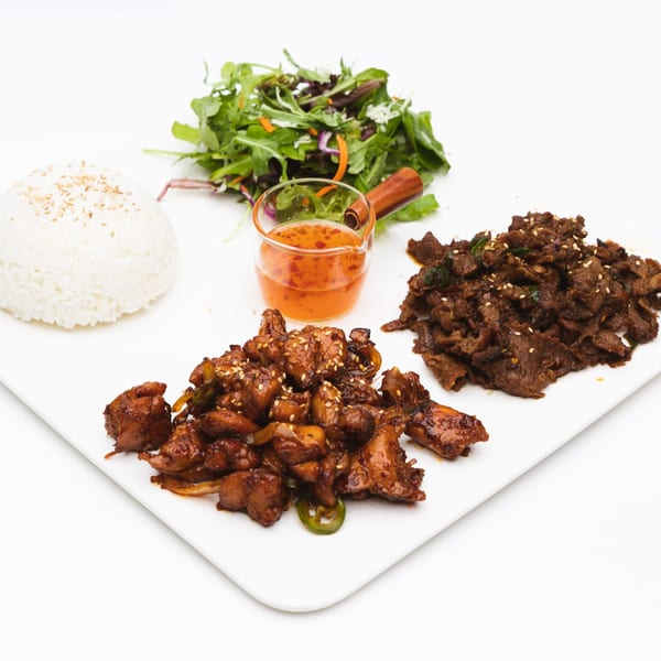 Korean BBQ chicken and beef, rice, salad, and chili sauce on a white plate.