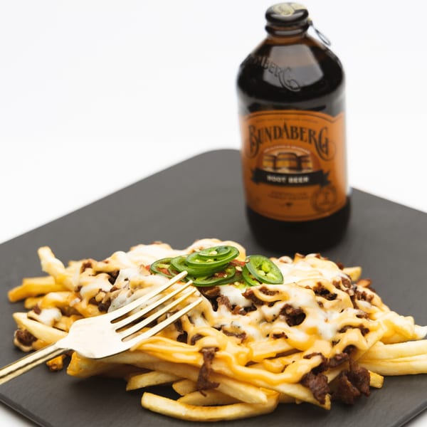 Korean bulgogi fries with melted cheese, jalapeños, and a Bundaberg root beer bottle.