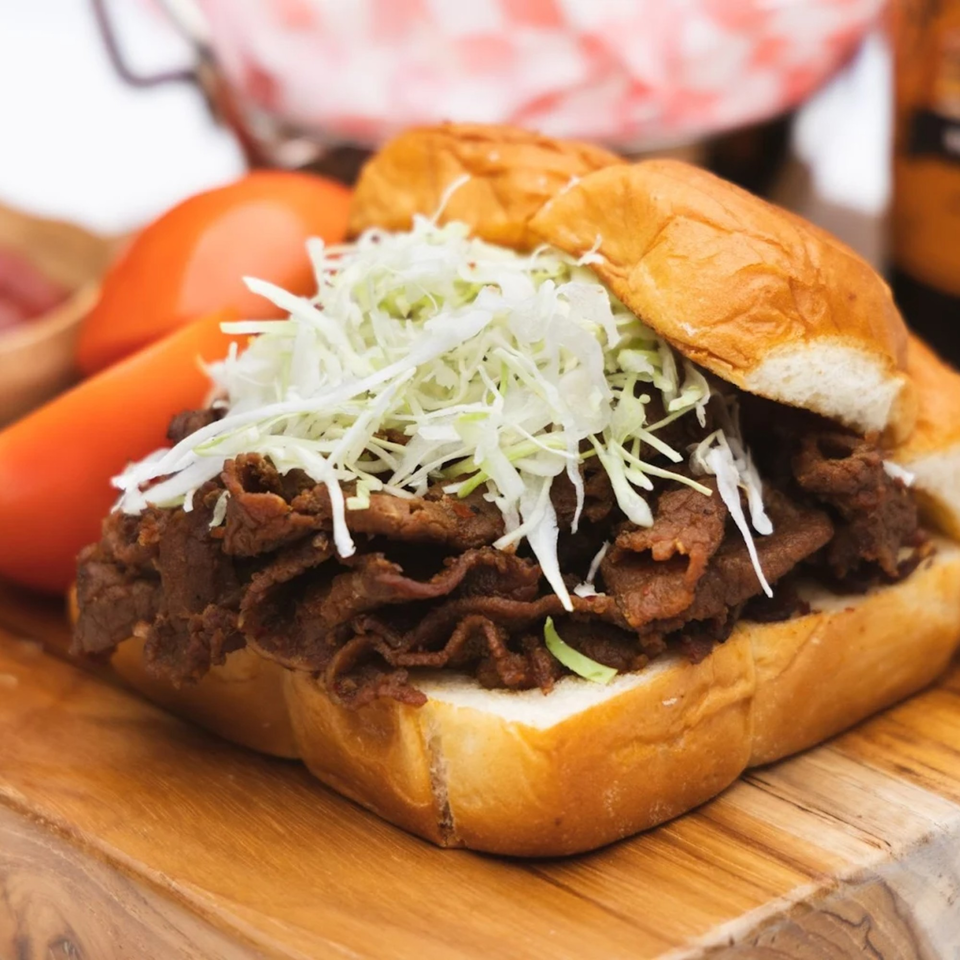 Corner Grille's Korean bulgogi sandwich with shredded cabbage on a wooden board.